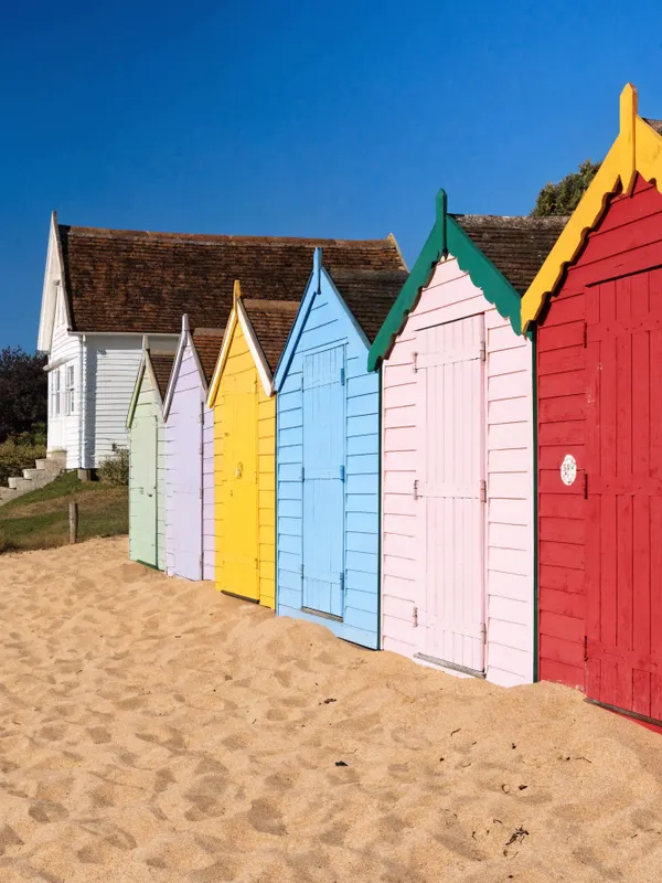 Colourful beach huts beside a white weatherboard seaside cottage